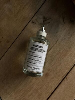 Close-up of Maison Margiela Replica perfume bottle on a wooden surface.