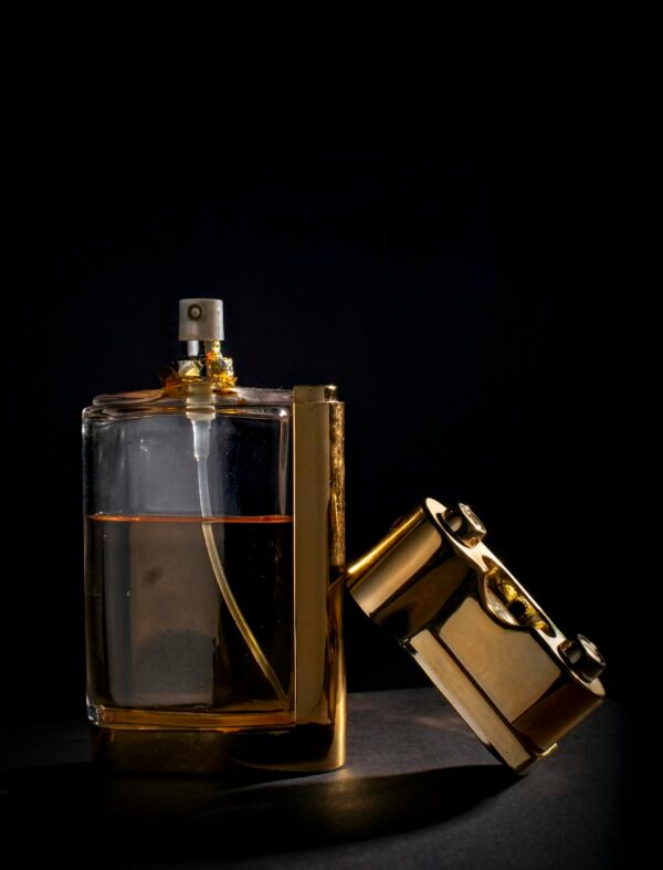 Sophisticated perfume bottle with gold details on a black backdrop, exuding luxury.